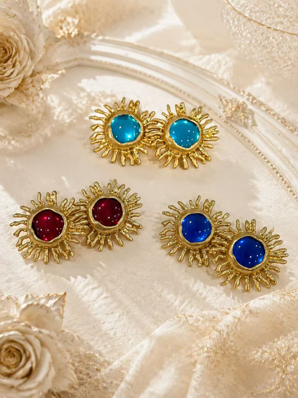 Gold-tone sunflower glass-style stud earrings in red, sky blue, and light blue