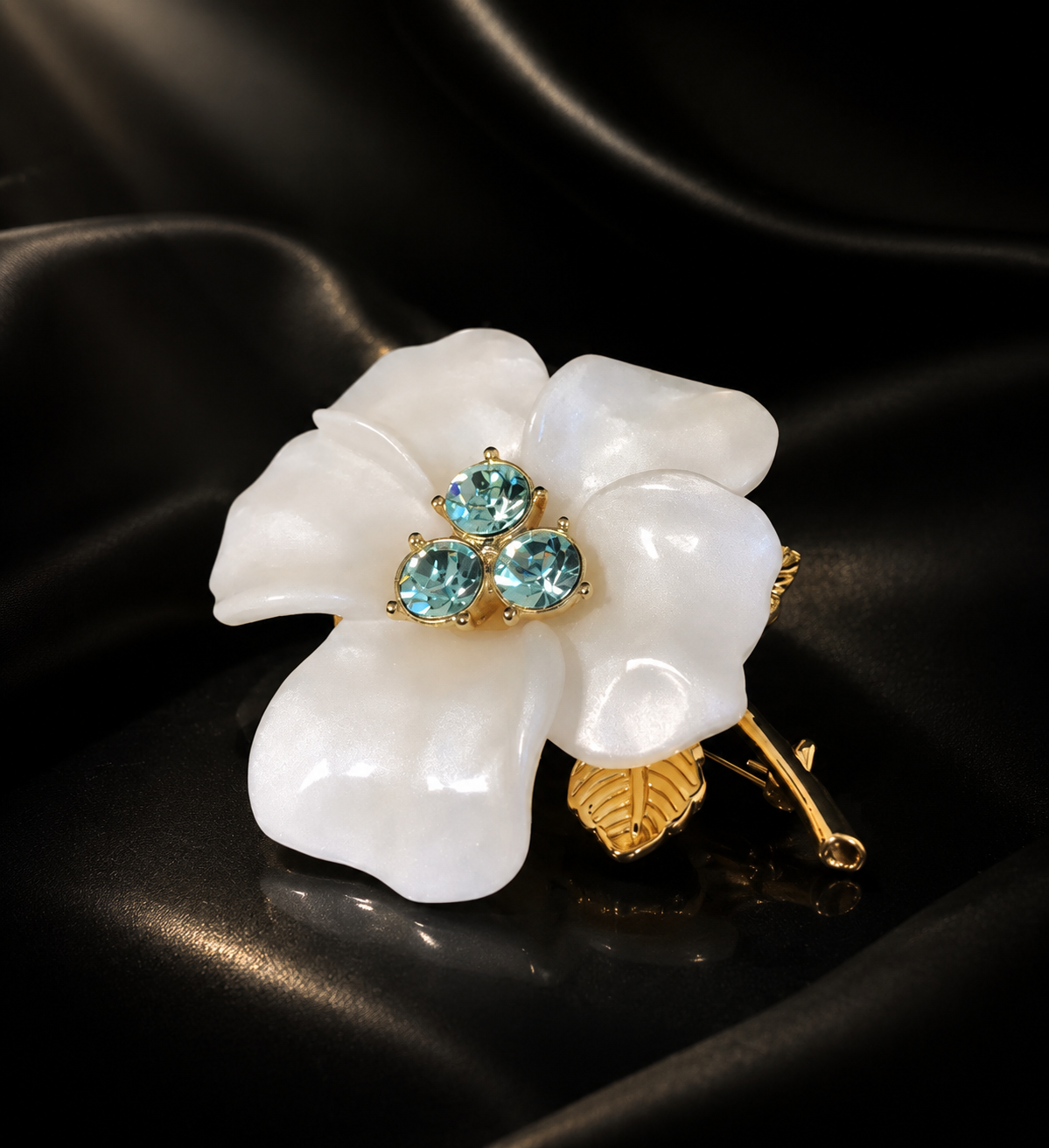 Gold-tone white flower brooch close view with blue crystal-style center