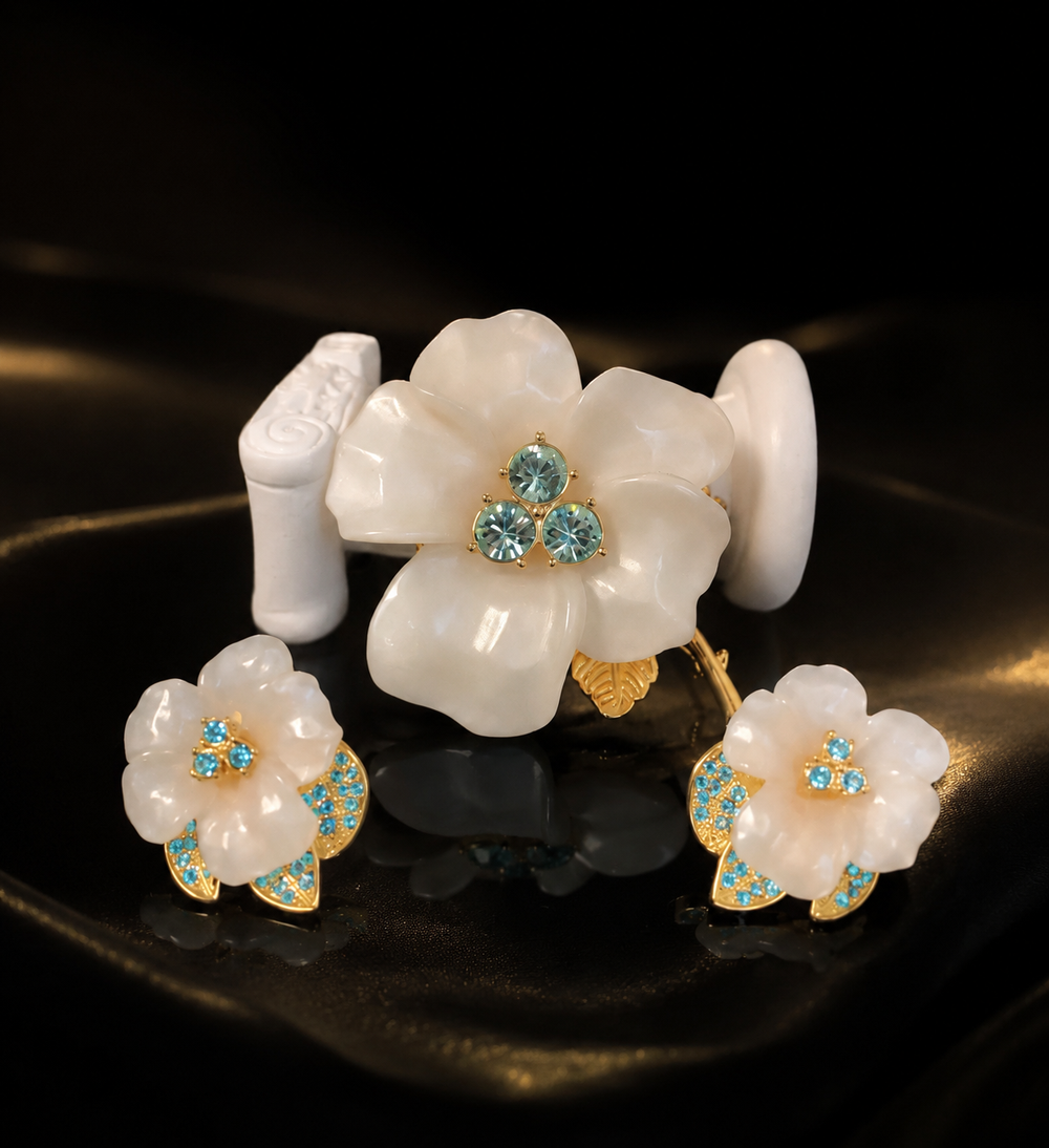 Gold-tone white flower brooch and stud earrings set with blue crystal-style accents