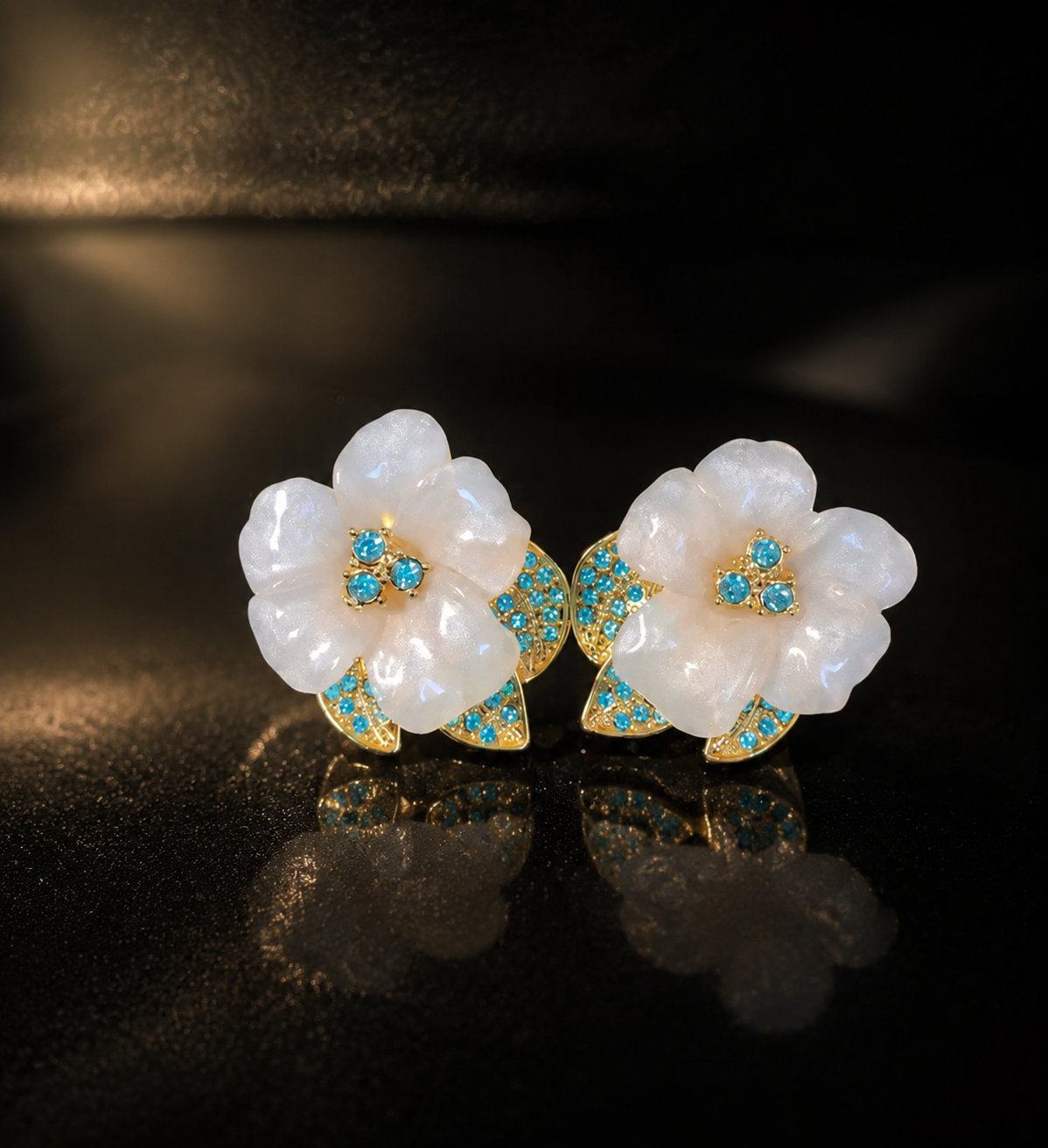 Gold-tone white flower stud earrings with blue crystal-style accents