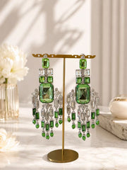 Green and clear crystal-style chandelier clip-on earrings on a gold display stand