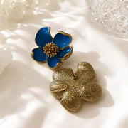 Light blue enamel floral stud earring shown from front and back on ivory fabric