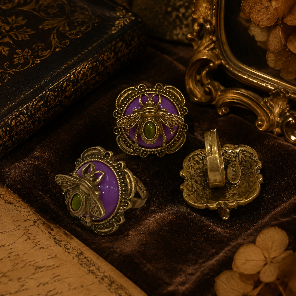 Gold-tone adjustable ring with an ornate honey bee motif, purple stone-style accent, and green cabochon-style center, front and back view
