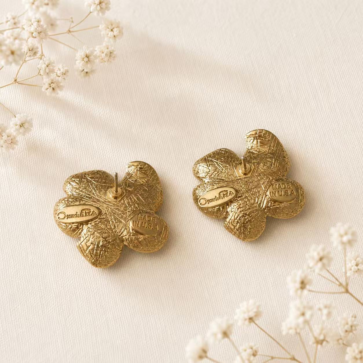 Back view of pink enamel floral stud earrings on ivory fabric