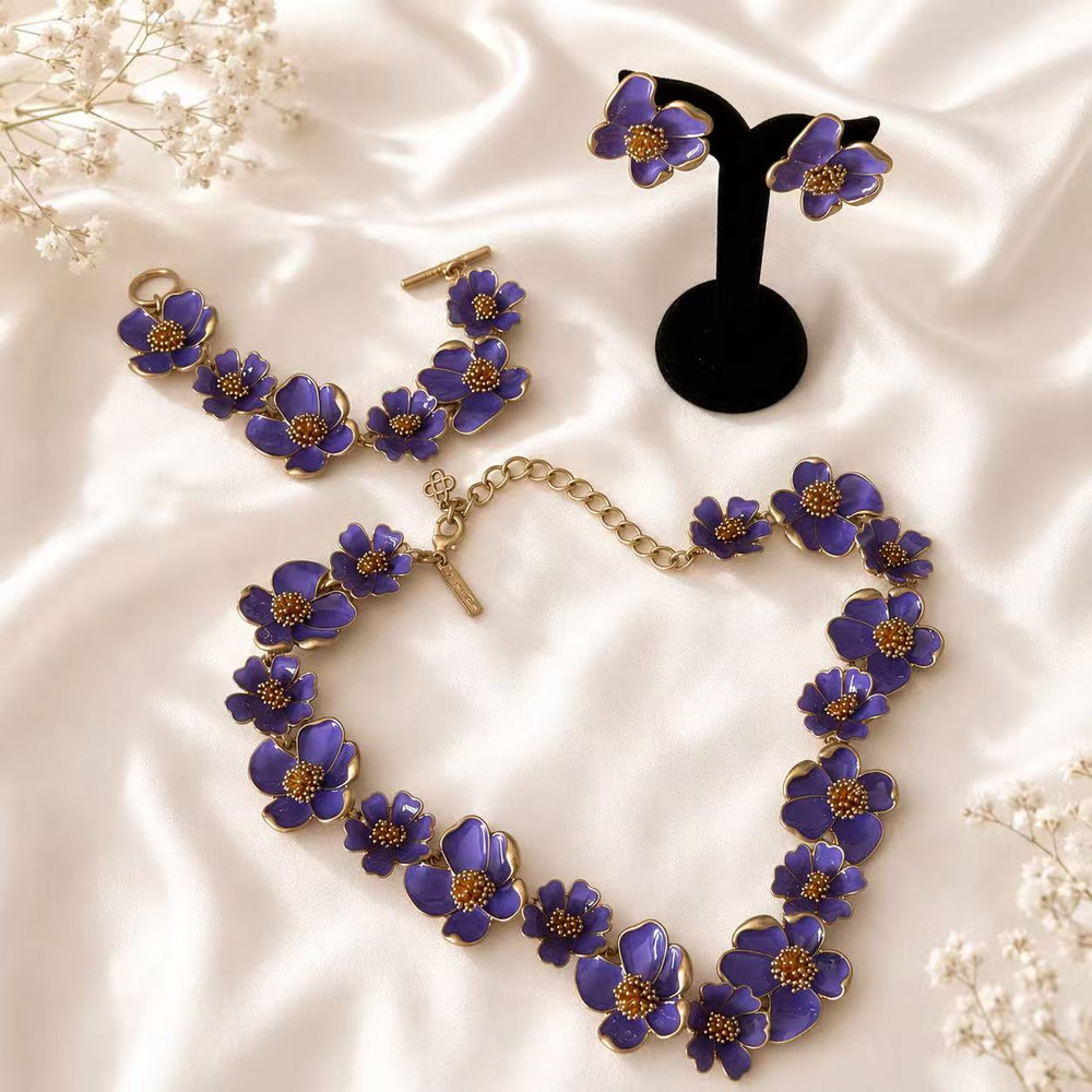 Purple enamel floral necklace, bracelet, and matching stud earrings complete set on ivory satin