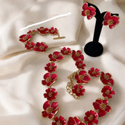 Red enamel floral jewelry set with necklace, bracelet, and stud earrings on ivory fabric
