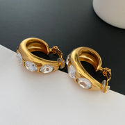 Side view of gold-tone wide hoop clip-on earrings showing hinged clip closures and clear round pads