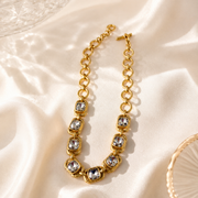 Gold-tone clear rhinestone-style chain necklace on light fabric view
