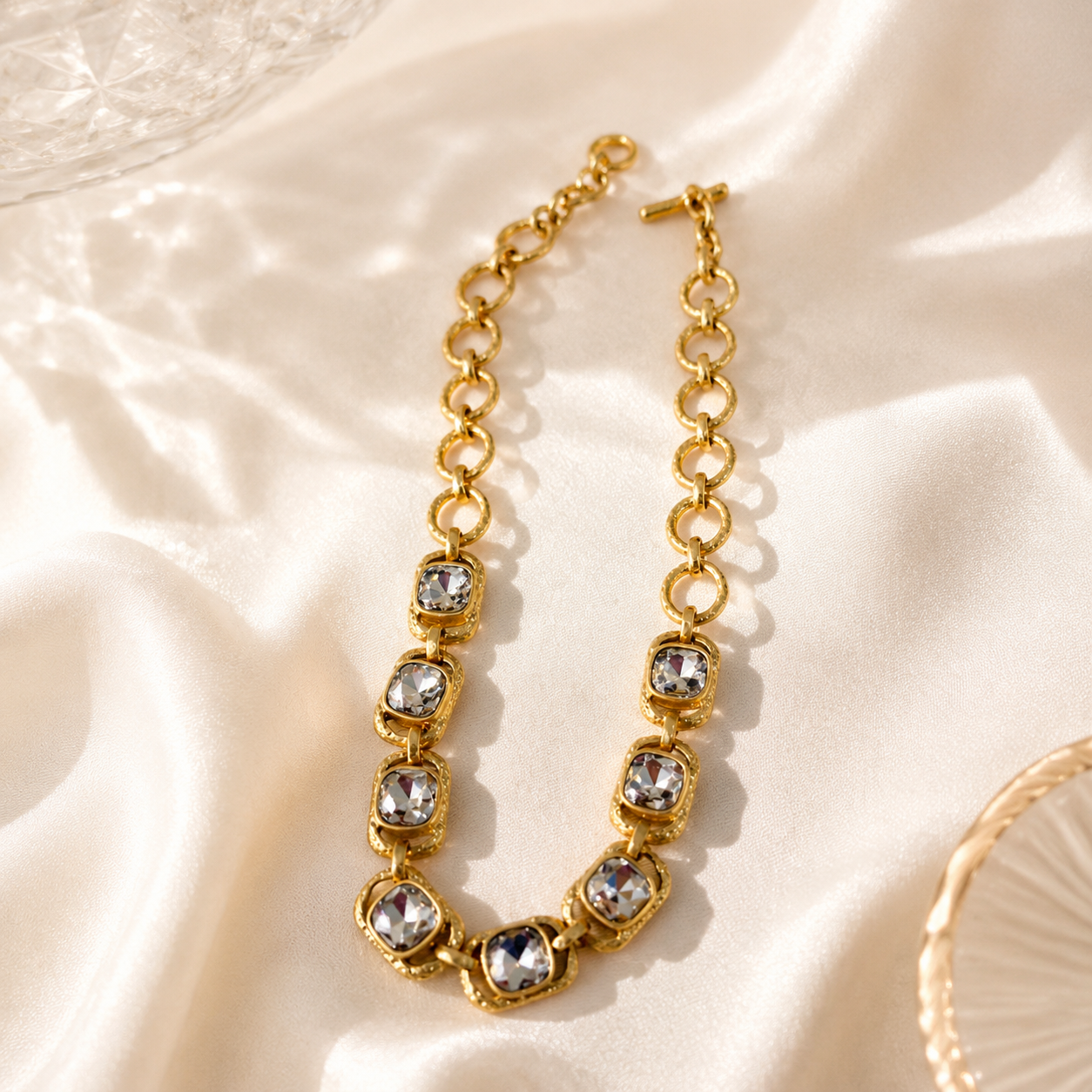 Gold-tone clear rhinestone-style chain necklace on light fabric view