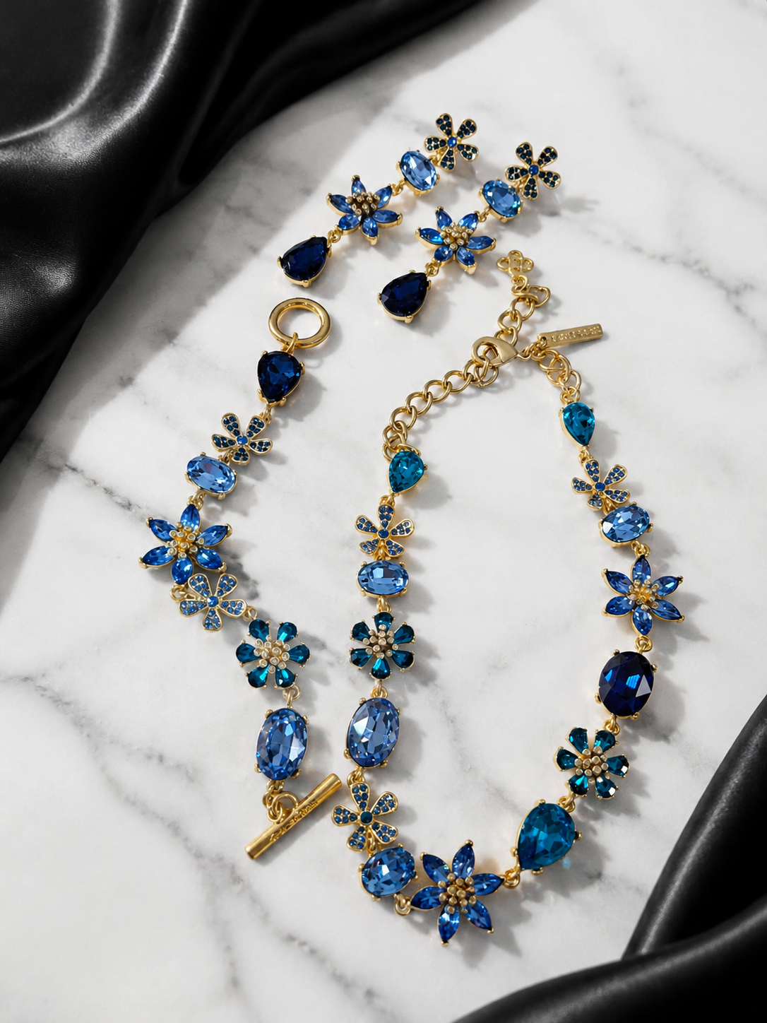 Blue gold-tone glass flower and teardrop jewelry set flat lay