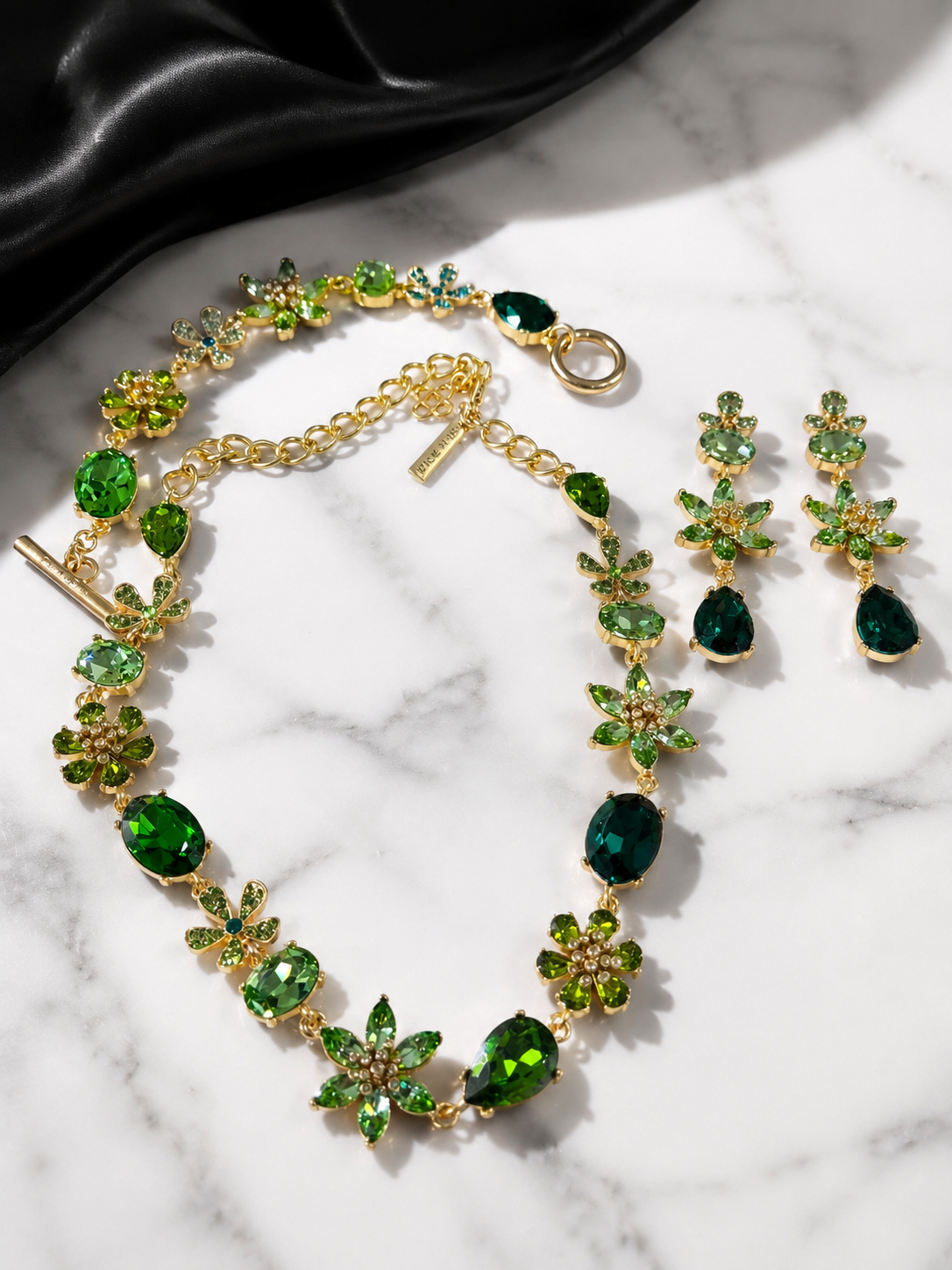 Green gold-tone glass flower and teardrop jewelry set flat lay