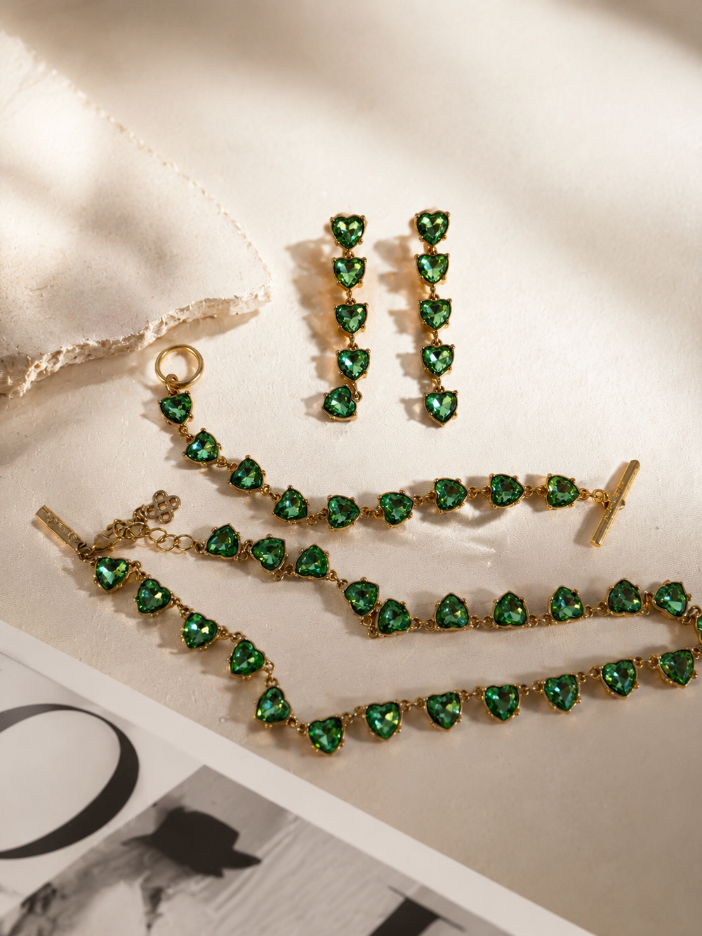 Gold-tone green crystal-style heart necklace, bracelet, and earrings jewelry set flat lay