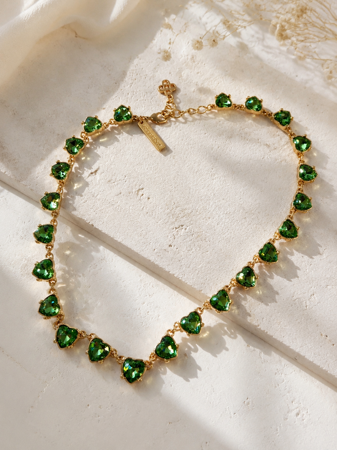Gold-tone green crystal-style heart necklace detail view