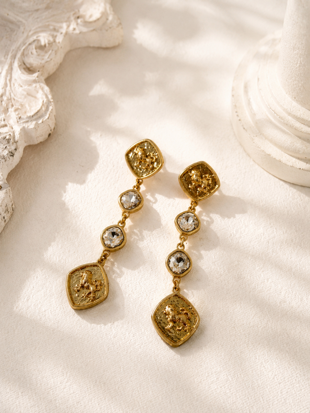 Gold-tone horse medallion crystal-style-style drop stud earrings flat lay
