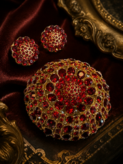 Gold-tone red crystal-style brooch and stud earrings set on dark red satin background