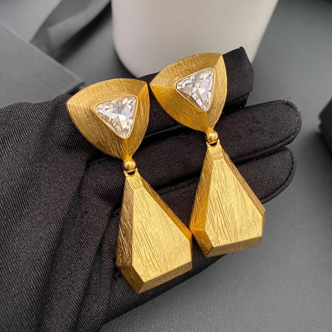 Vintage-inspired rhinestone geometric teardrop clip-on earrings held on a black glove