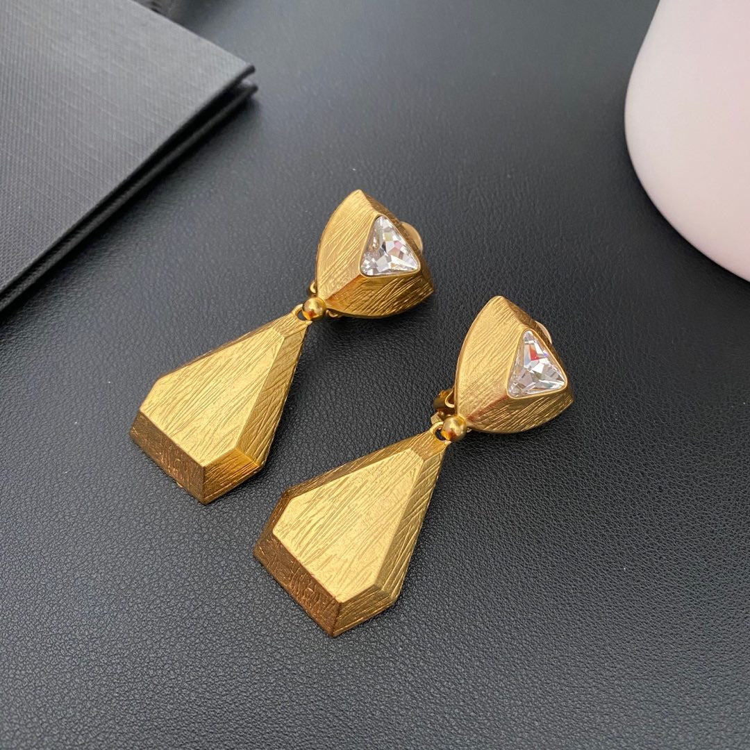 Vintage-inspired rhinestone geometric teardrop clip-on earrings on a black surface