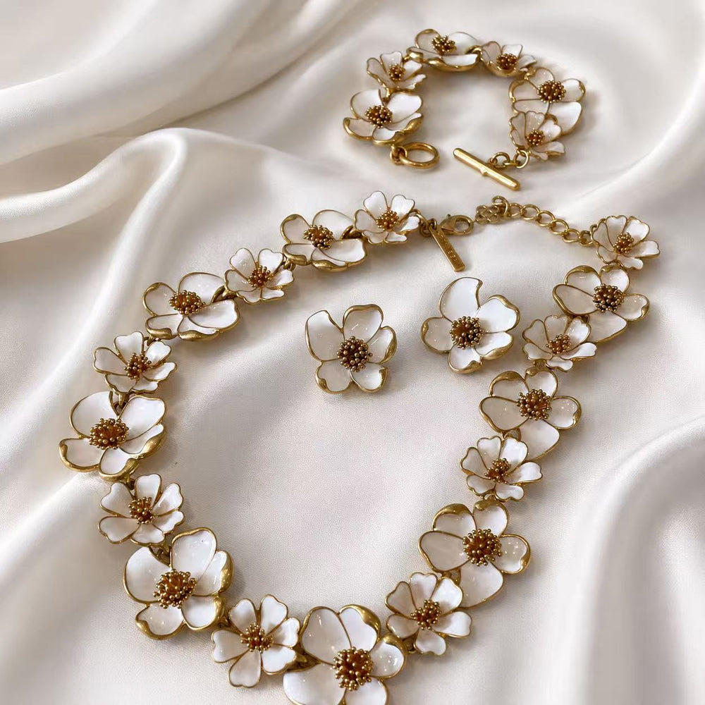 White enamel floral necklace, bracelet, and matching stud earrings complete set on white satin