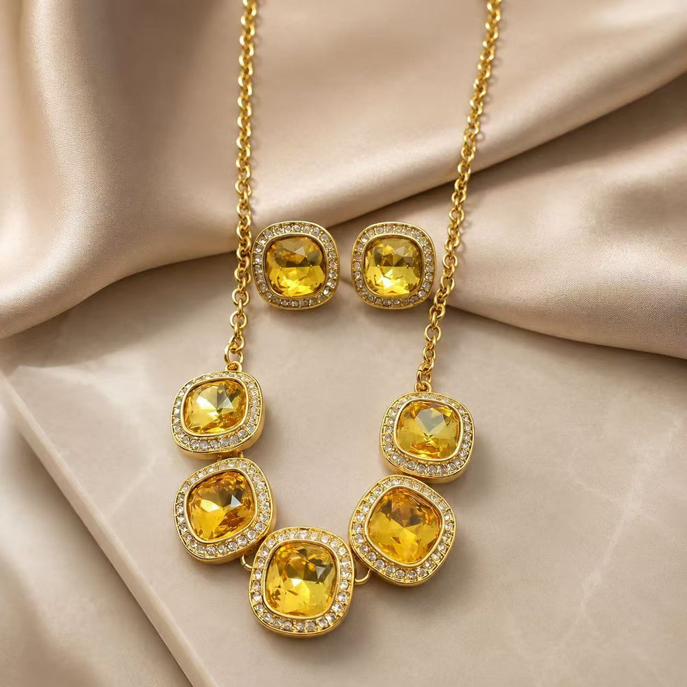 Yellow rhinestone necklace and matching stud earrings set on champagne fabric